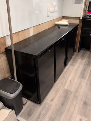 an image of a kitchen with a black refrigerator and trash can