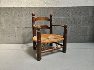 a small wooden chair with a rope on the back of it