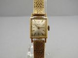 an image of a gold wrist watch with a chain around it