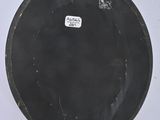 an old black plate with a tag on it sitting on a white surface
