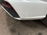 the rear end of a white car with a red tail light
