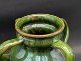 a green vase with a handle on a black background