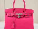 un sac à main rose muni d'un cadenas, posé sur une table