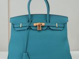 un sac à main en cuir bleu muni d'un fermoir doré sur la poignée