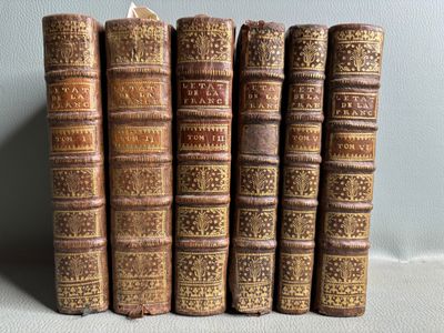six old books are lined up on a table