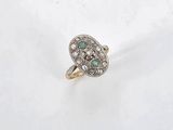 a close up of a diamond and emerald ring on a white surface