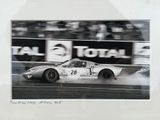 framed photograph of a race car speeding on a track with a crowd watching