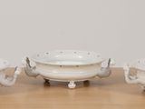 three white dishes sitting on top of a wooden table next to each other