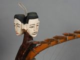 a sculpture of two faces on a tree branch