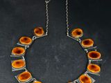 un collier composé de cercles orange et argentés sur fond noir