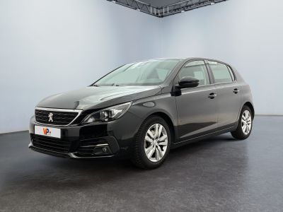 La voiture grise est garée dans une grande pièce au sol noir.