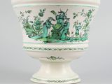 a green and white vase with a picture of a man and a woman on it