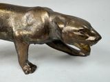 a bronze statue of a cat on a white surface