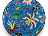 an image of a blue plate with flowers and leaves on it