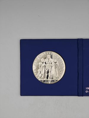 un livre ouvert, avec une pièce d'argent posée sur sa couverture bleue