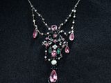 une femme portant un collier orné de pierres roses et vertes