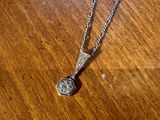 un collier en argent posé sur une table en bois, orné d'un pendentif en argent
