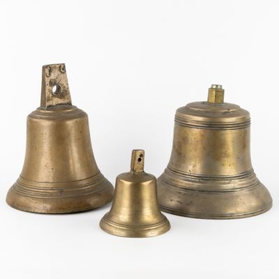 three antique brass bells on a white background