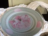 une assiette blanche ornée d'une fleur rose, dans une boîte