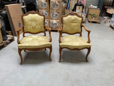 pair of antique chairs in a warehouse with boxes and boxes in the background
