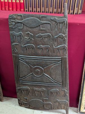une vieille porte en bois ornée de sculptures, devant une bibliothèque