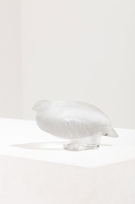 une sculpture en verre représentant un oiseau perché sur une surface blanche
