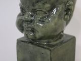 a green statue of a baby head on a green base