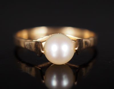 un gros plan d'une bague ornée d'une perle sur un fond noir