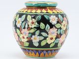 un vase noir orné de fleurs colorées sur fond blanc