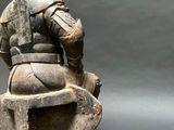 statue of a man sitting on a chair with a helmet on his head