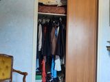 a closet in the corner of a room with clothes hanging on it