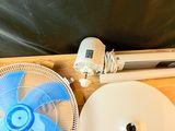 un ventilateur posé sur une palette en bois, à côté d'un bac en plastique