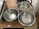 three metal bowls sitting on a wooden table