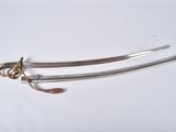 pair of two swords on a white surface with a gold handle