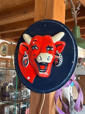 a red bull head on a blue plate hanging from a wooden pole