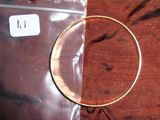 une photo d'un bracelet rigide en or posé sur un tissu rouge