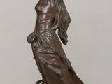 bronze statue of a woman holding a bird on a wooden table