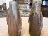 deux vases posés sur une table, avec un mur de pierre en arrière-plan