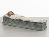 statue of a woman laying on a stone slab with a blanket on it