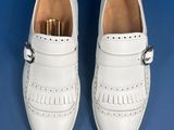 white leather shoes with tassels and buckles on a blue background