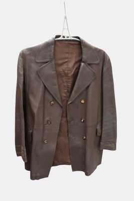 une veste en cuir marron suspendue à un cintre sur un mur blanc