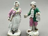 paire de figurines en porcelaine représentant un homme et une femme tenant un journal