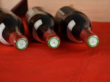 three bottles of wine are lined up on a red cloth