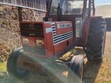 a red tractor parked in front of a barn