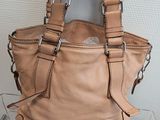 beige leather handbag sitting on a clear acrylic display case