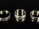 three silver rings sitting on top of a table next to each other