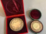 l'image d'une médaille d'or dans un coffret rouge posé sur un fond blanc
