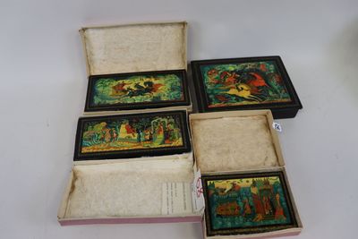 quatre petites boîtes ornées de peintures, posées sur une table