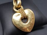 a close up of a gold heart pendant on a black pillow