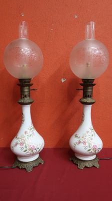 une paire de lampes en verre blanc et rose posées sur un support rouge